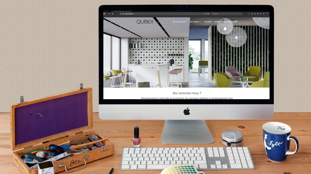 Web de Qubex en un monitor, con una imagen de interiorismo y acceso al espacio privado